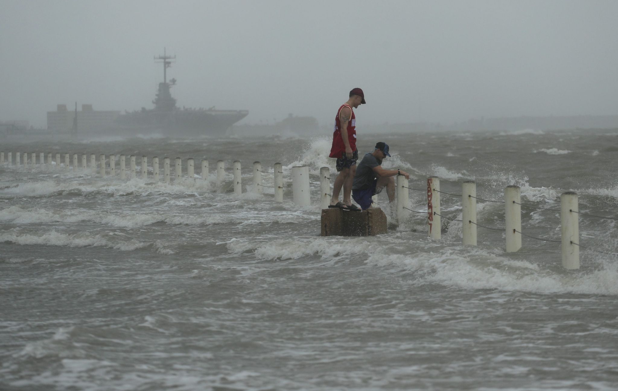 Two men stand near a sea wall as Hurricane Hanna makes landfall, Saturday, July 25, 2020, in Corpus Christi, Texas.  The National Hurricane Center said Saturday morning that Hanna's maximum sustained winds had increased and that it was expected to make landfall Saturday afternoon or early evening. (AP Photo/Eric Gay)